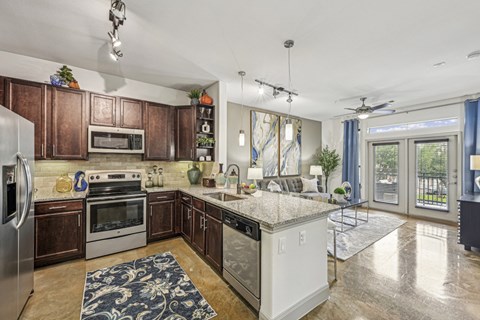 Kitchen view showing a spacious layout with dark wood cabinets and pendant lighting at Allusion at West University apartments in Houston, TX